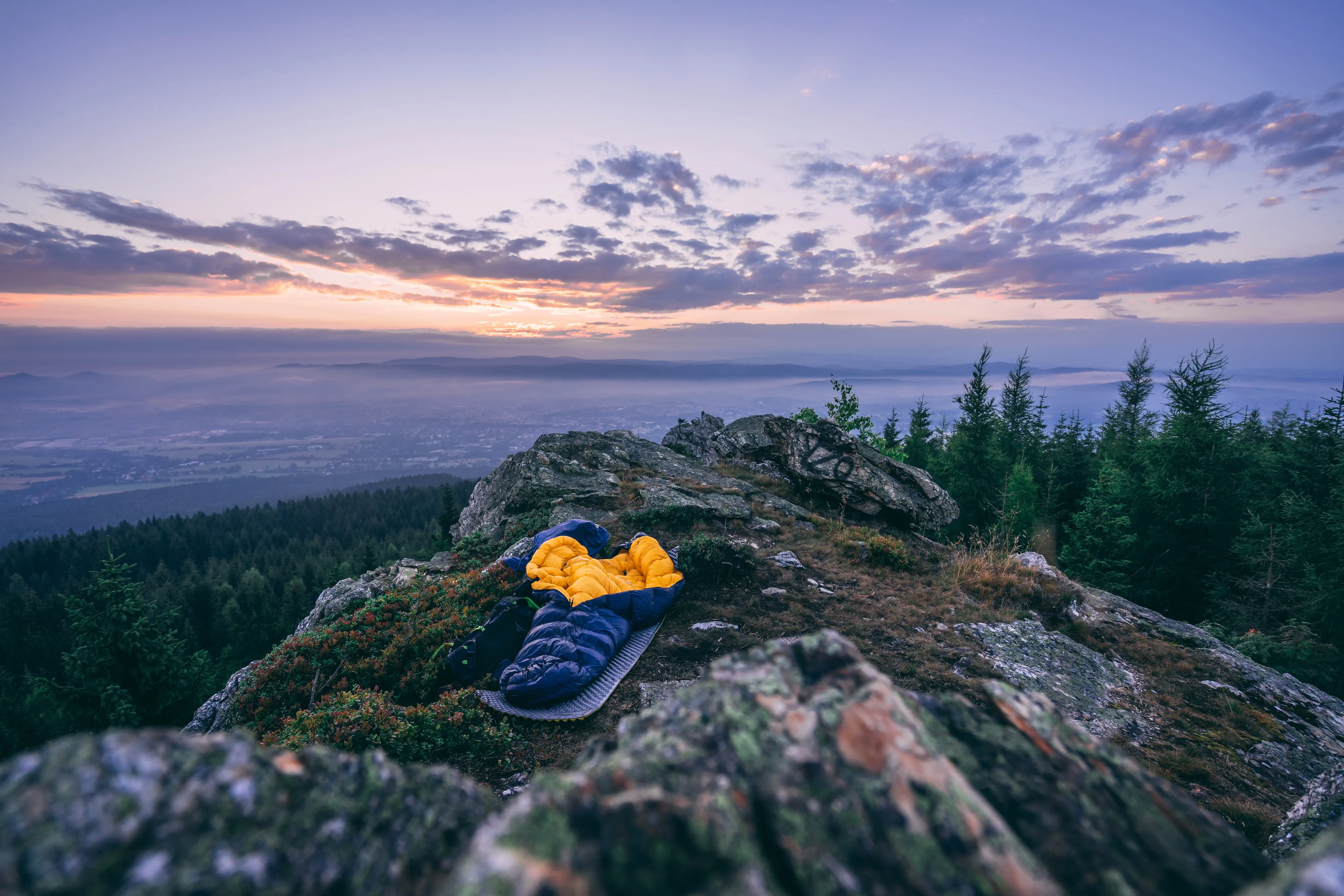 Offener gelb-blauer Schlafsack auf einem Berggipfel