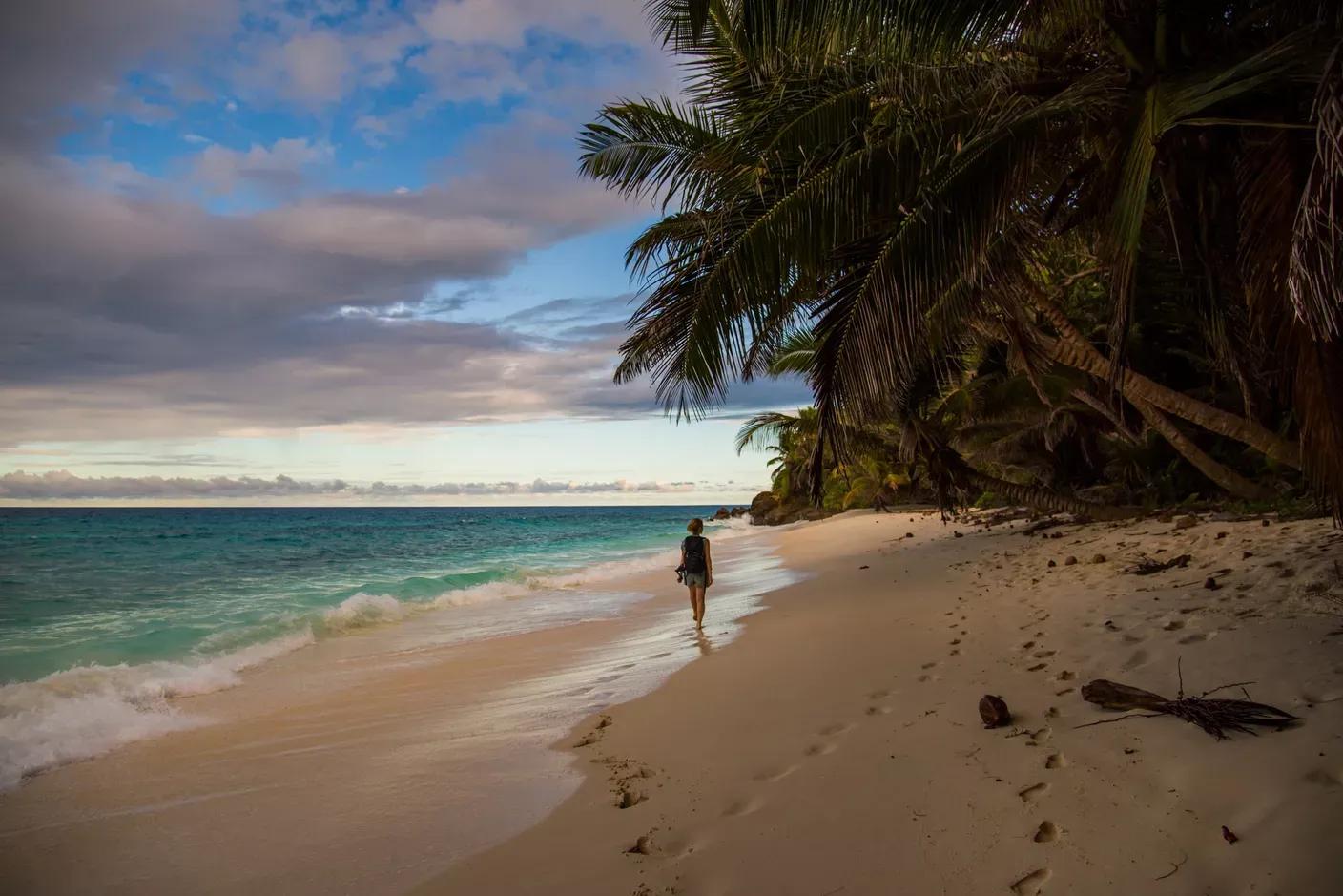 Frau, die am Strand von North Island spazieren geht, umgeben von Meer und Palmen