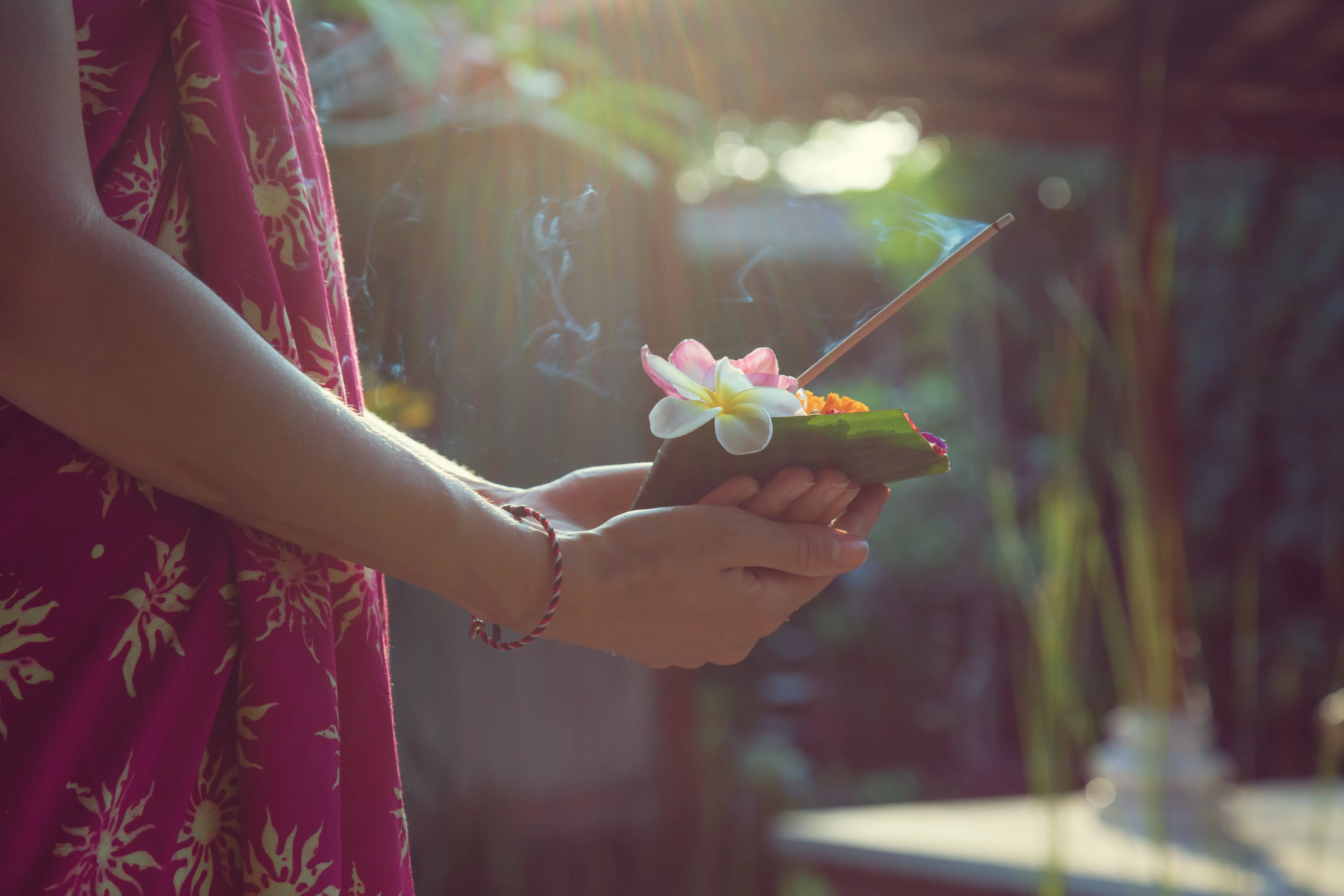Hands holding leaf with flower and incense stick