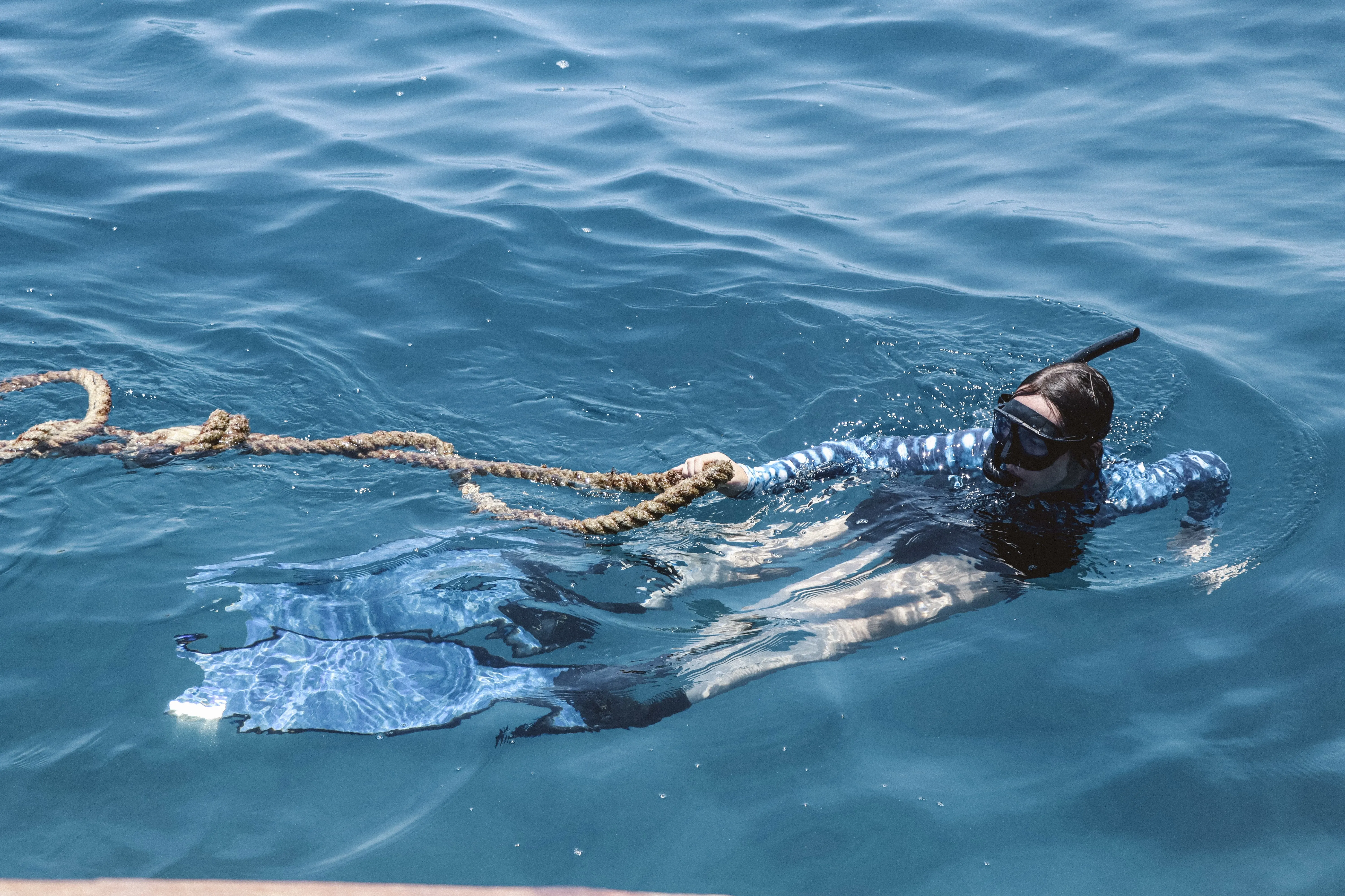 Volunteers in the water in the Maldives with a rope and snorkelling equipment.