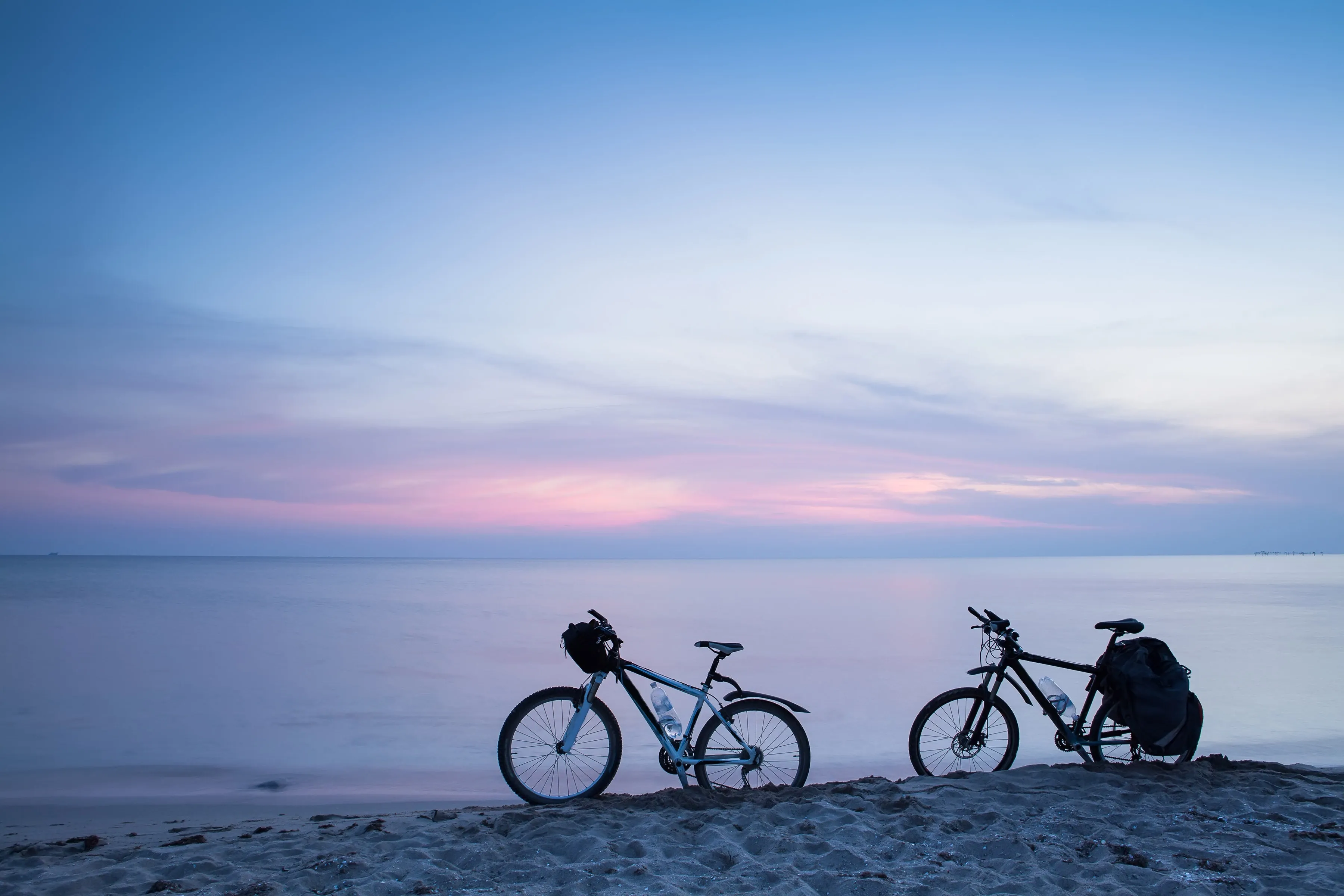 Zwei Fahrräder am Strand während der blauen Stunde