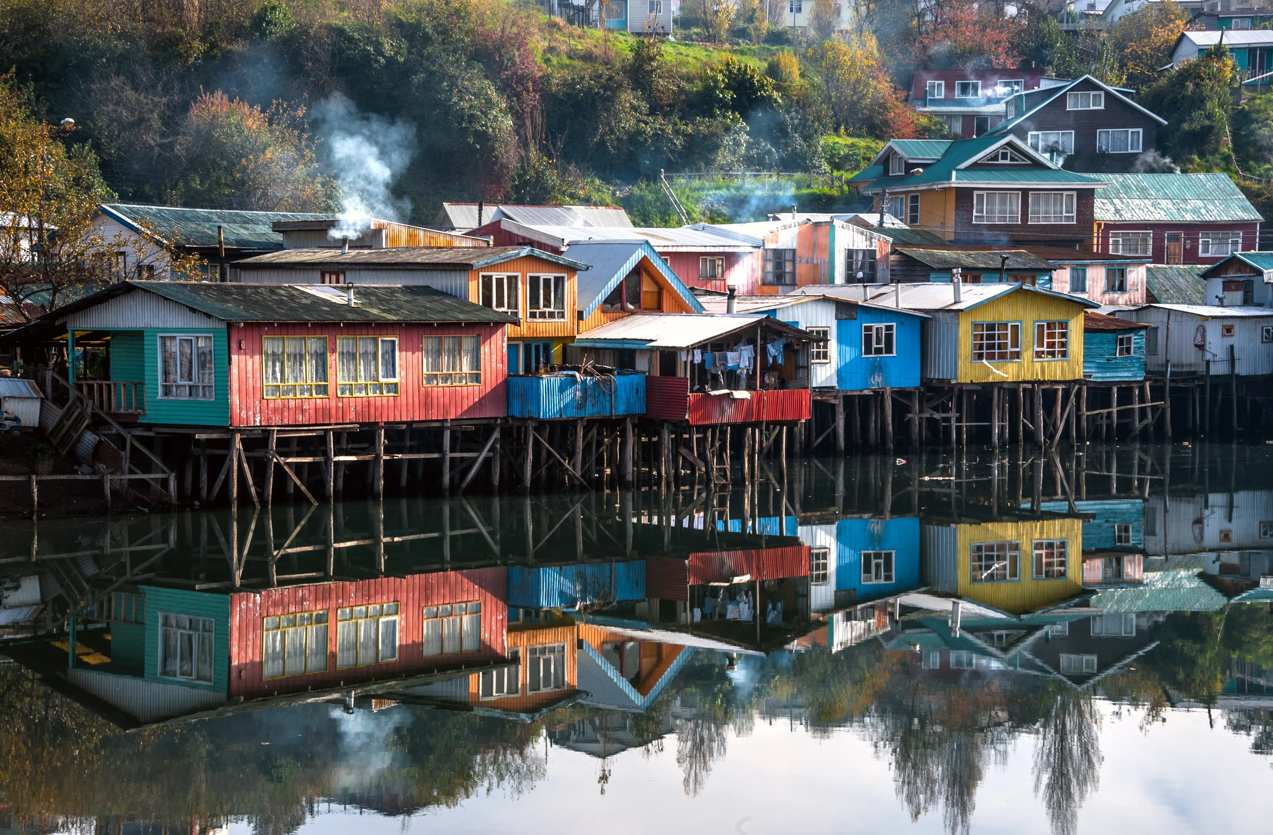 Colourful houses on stilts are reflected in the water