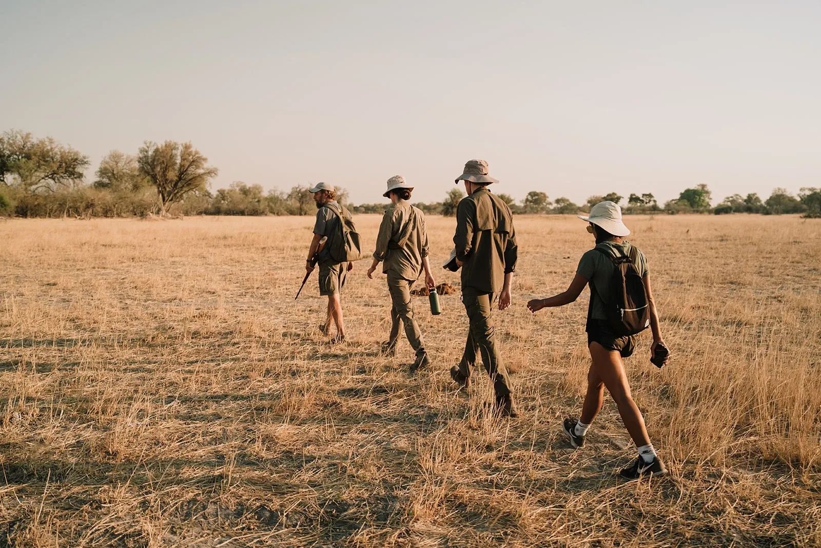 Four people walk through the Botswana bush