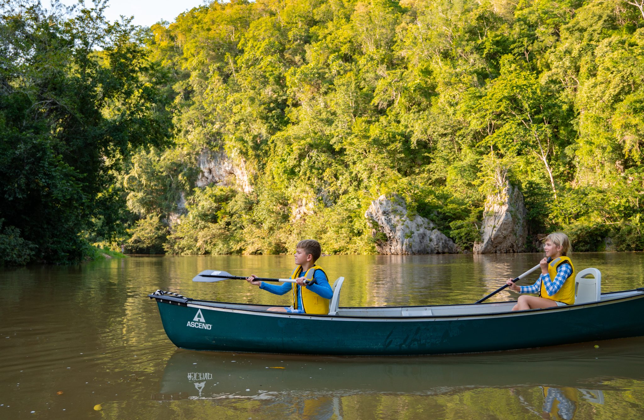 Children kayaking by the river beach
