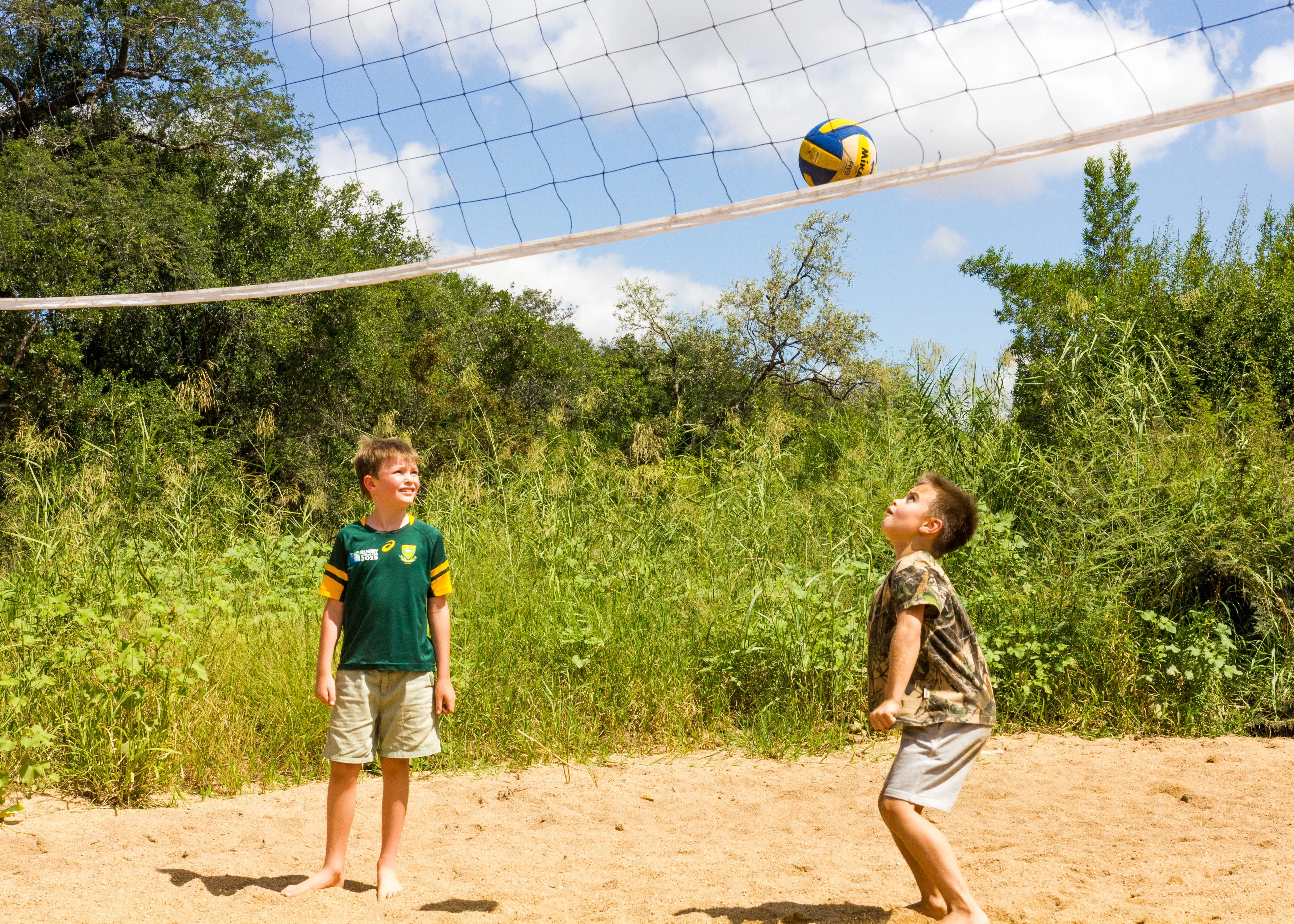 Kinder spielen Volleyball im trockenen Flussbett gegenüber dem Camp
