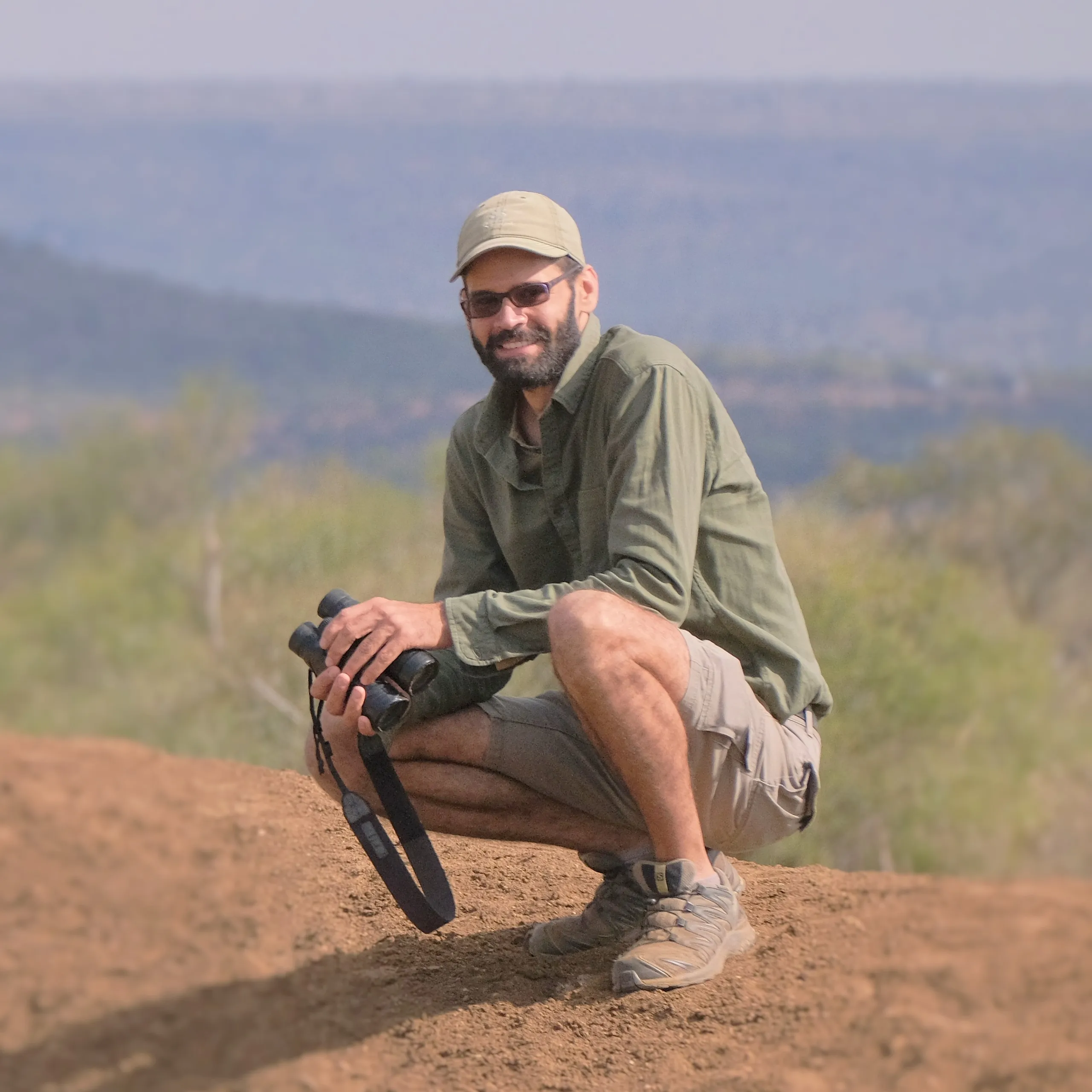 Guide sitting on the ground with binoculars in his hands