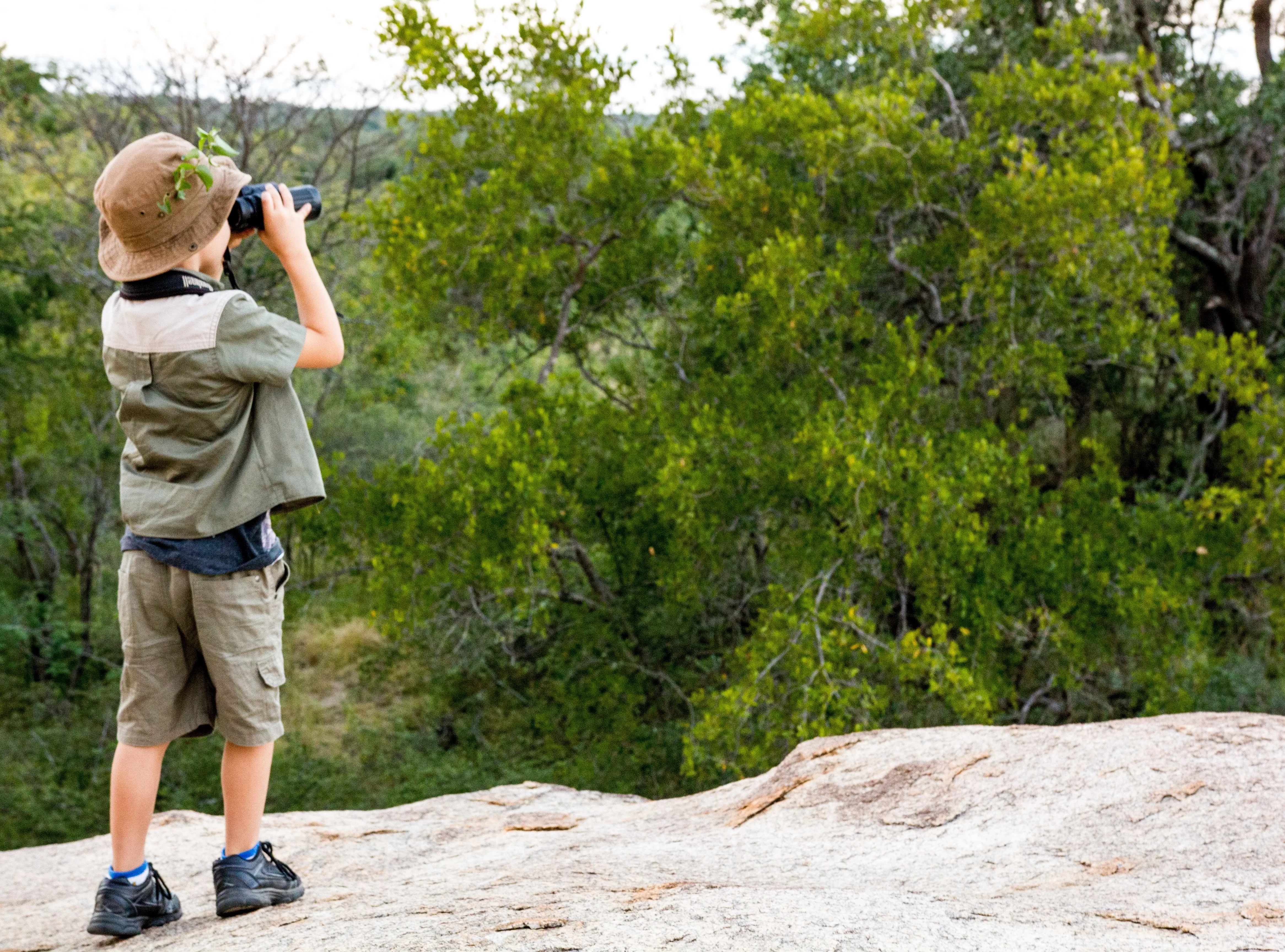 Kind betrachtet einen Busch durch ein Fernglas