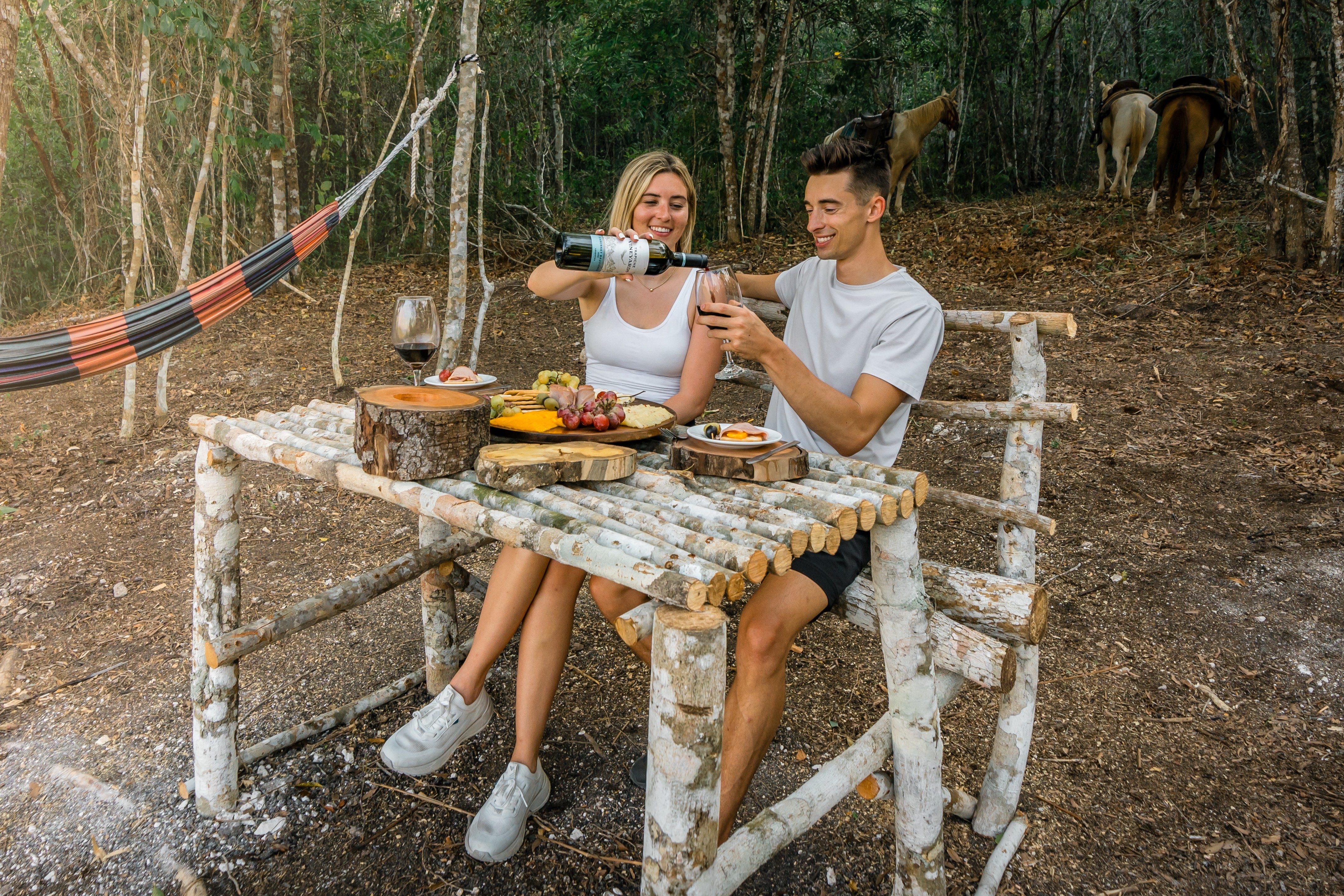 Couple enjoying a wine and charcuterie board by horses
